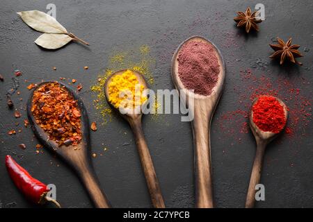 épices et condiments en cuillères sur fond noir Banque D'Images