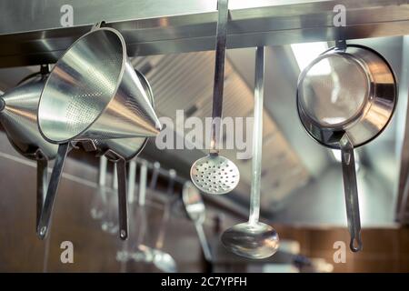 Ustensiles de cuisine en laiton, accessoires de chef. Cuisine suspendue en cuivre avec mur en carreaux blancs Banque D'Images