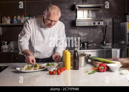 Saupoudrer d'épices Chef sur plat en cuisine commerciale Banque D'Images