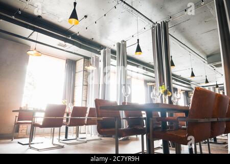 Hall à demi-éclairage de style loft dans un restaurant mexicain avec cuisine ouverte sur le fond. En face de la cuisine il y a des tables en bois avec mu Banque D'Images