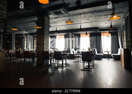 Hall à demi-éclairage de style loft dans un restaurant mexicain avec cuisine ouverte sur le fond. En face de la cuisine il y a des tables en bois avec mu Banque D'Images