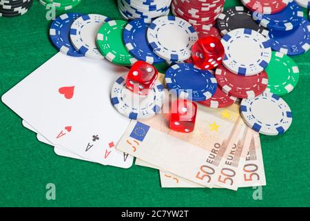 dés, quatre as, jetons de poker colorés et billets en euros sur une table verte Banque D'Images