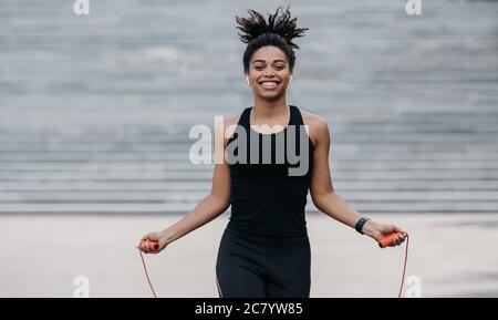 Fille dans les vêtements de sport avec entraînement de tracker de forme physique avec corde de saut Banque D'Images