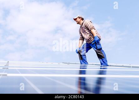 Énergie solaire. Ingénieur électricien homme travaille dans la station solaire sur le toit contre le ciel bleu dans la journée ensoleillée. Développement solaire énergie alternative Banque D'Images