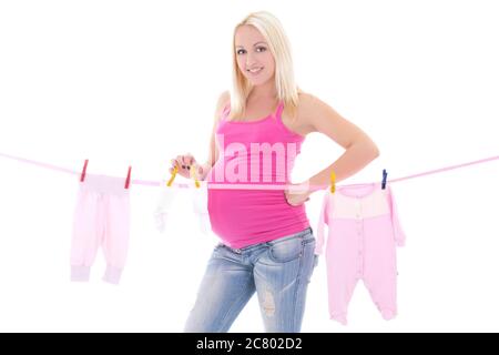 femme enceinte heureuse qui pendait des vêtements d'enfant isolés sur fond blanc Banque D'Images