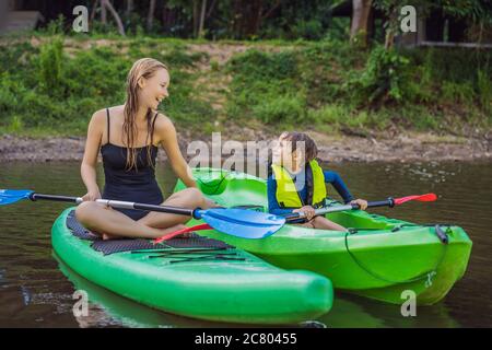 Joyeux jeune garçon tenant la pagaie dans un kayak sur la rivière, profitant d'une belle journée d'été Banque D'Images