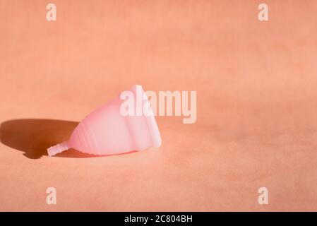 Coupe menstruelle sur fond rose avec l'ombre . Le concept des jours critiques pendant les vacances et l'été. Banque D'Images