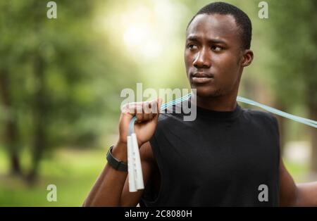 Homme noir sérieux avec entraînement de corde de saut au parc Banque D'Images