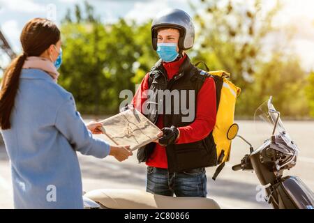 Livraison Guy sur Scooter livraison de paquet à fille debout à l'extérieur Banque D'Images