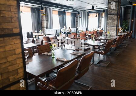 Hall à demi-éclairage de style loft dans un restaurant mexicain avec cuisine ouverte sur le fond. En face de la cuisine il y a des tables en bois avec mu Banque D'Images