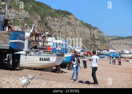 UN HOMME PRENANT UNE PHOTO D'UNE FEMME SUR UNE PLAGE DE BORD DE MER DANS LA VIEILLE VILLE DE HASTINGS Banque D'Images