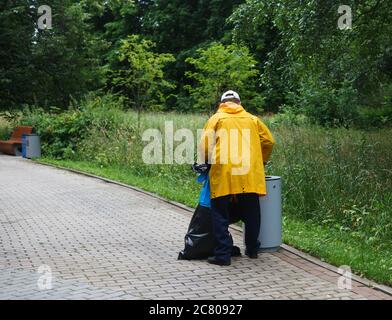 Homme avec des sacs poubelle pour trier les déchets dans un parc public. Vue arrière Banque D'Images