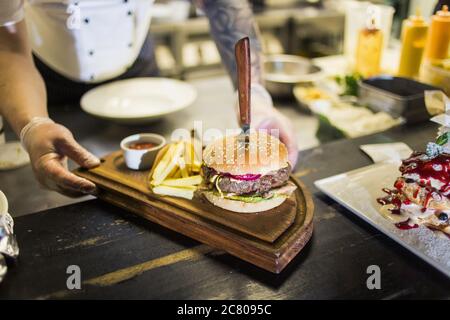 Deux délicieux hamburgers faits maison appétissants, utilisés pour hacher du bœuf. Sur la table en bois. Les hamburgers sont des couteaux insérés. Banque D'Images