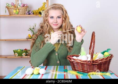 jeune femme attrayante avec cheveux longs et bouclés peignant des oeufs de pâques Banque D'Images