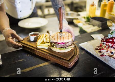 Deux délicieux hamburgers faits maison appétissants, utilisés pour hacher du bœuf. Sur la table en bois. Les hamburgers sont des couteaux insérés. Banque D'Images