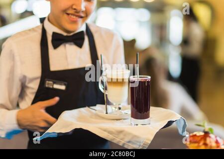 Gros plan de la main du serveur en notant le menu sur la tablette. Jeune femme commandant de la nourriture à un serveur au restaurant. Jeune belle femme pensant à la nourriture à Banque D'Images