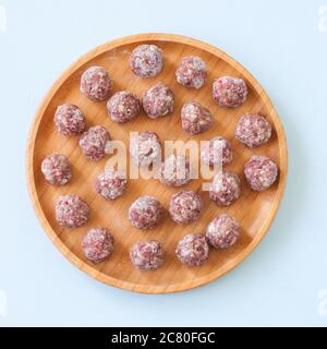 Boulettes de viande crues sur une plaque de bois. Vue de dessus Banque D'Images