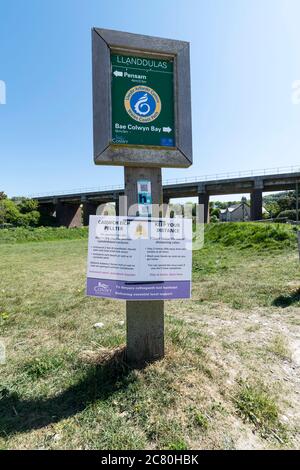 Llanddulas North Wales Coast Path signe avec Covid 19 message d'avertissement sur la distanciation sociale en gallois et en anglais Banque D'Images