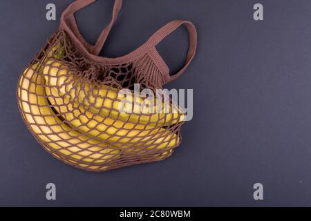 Bananes jaunes dans un sac à ficelle beige sur fond noir, espace de copie Banque D'Images