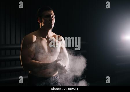 Bodybuilder brutal clapping les mains avec le talc avant de soulever la barbell à la salle de gym. Banque D'Images