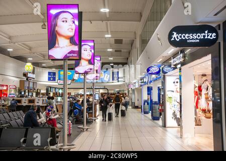 Intérieur du salon de départ de l'aéroport de Stansted à Londres. Coin salon à l'extérieur de divers magasins, y compris Accessorize et Boots et autres. Banque D'Images