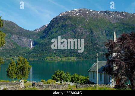 Norvège, cascade nommée Feigumfossen à Lusterfjord avec église et cimetière en premier plan Banque D'Images