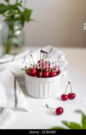 Cerise fraîche dans un bol en céramique sur une table blanche. Vue de dessus. Photo verticale Banque D'Images