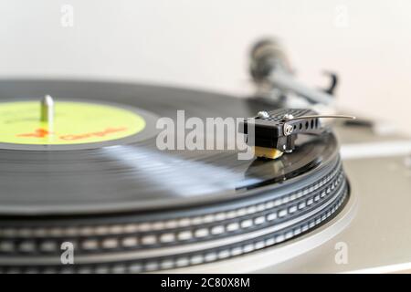 Gros plan d'un disque avec un bras-levier en forme de S avec stylet jouant LP vinyle record sur la platine d'entraînement de courroie. Flou de mouvement. Arrière-plan simple. Banque D'Images