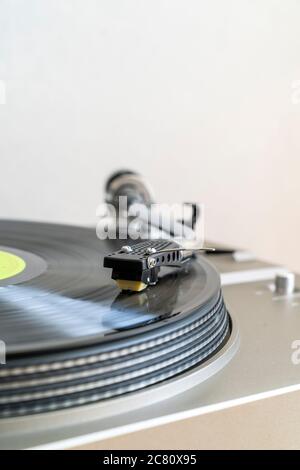 Gros plan d'un disque avec un bras-levier en forme de S avec stylet jouant LP vinyle record sur la platine d'entraînement de courroie. Flou de mouvement. Arrière-plan simple. Banque D'Images