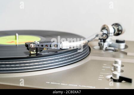 Gros plan d'un disque avec un bras-levier en forme de S avec stylet jouant LP vinyle record sur la platine d'entraînement de courroie. Flou de mouvement. Arrière-plan simple. Banque D'Images