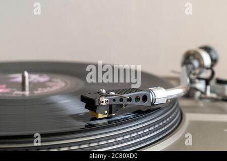 Gros plan d'un disque avec un bras-levier en forme de S avec stylet jouant LP vinyle record sur la platine d'entraînement de courroie. Flou de mouvement. Arrière-plan simple. Banque D'Images