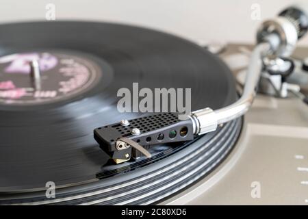 Gros plan d'un disque avec un bras-levier en forme de S avec stylet jouant LP vinyle record sur la platine d'entraînement de courroie. Flou de mouvement. Arrière-plan simple. Banque D'Images