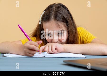 Hispanique adolescente école ou étudiant d'université écrit dans le cahier de travail faire des devoirs ou se préparer à l'examen assis à bureau Banque D'Images