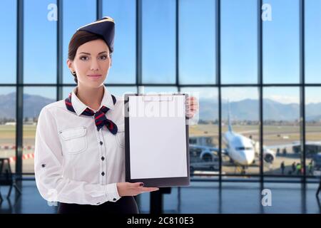 été, vacances et voyage concept - belle hôtesse tenant vide presse-papiers dans l'aéroport Banque D'Images