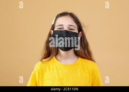 Enfant masqué - protection contre le virus de la grippe. Petite fille caucasienne portant un masque pour protéger les pm2,5. Armes biologiques. Bébé sur une orange Banque D'Images