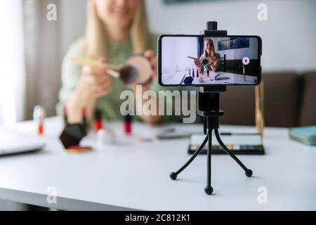 un blogueur de maquillage qui enregistre des vidéos avec un téléphone pour les médias sociaux à la maison Banque D'Images