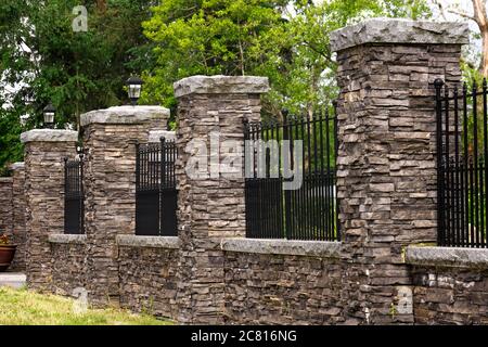 Une clôture en pierre à piliers avec des décors en fer forgé noir à l'avant d'une propriété résidentielle de Maple Ridge, B. C. Canada. Banque D'Images