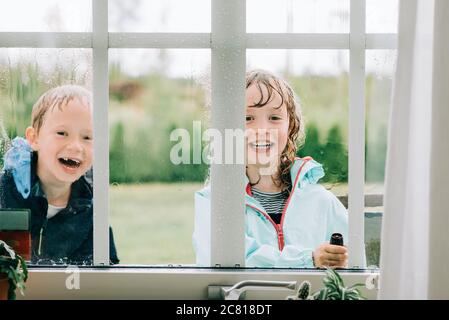 frère et sœur pulvérisant les fenêtres avec de l'eau tout en jouant Banque D'Images