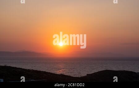 Couleur orange coucher de soleil sur l'eau de mer. Spectaculaire paysage magique de lever de soleil en mer Egée Grèce. Silhouette de montagne et reflets dorés sur les ondulations Banque D'Images