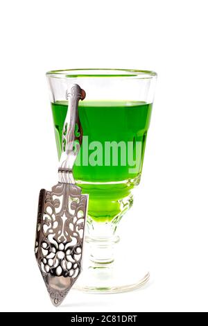 Boisson alcoolisée, stimulant créatif et style de vie bohème thème avec verre d'absinthe vert et cuillère en acier inoxydable isolée sur le dos blanc Banque D'Images