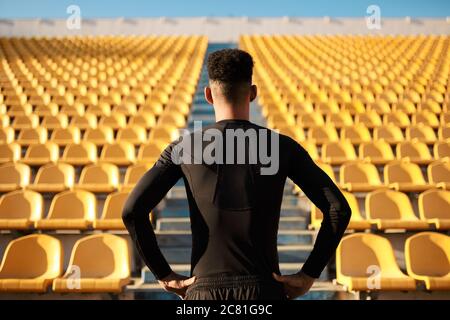 Vue arrière du sportif afro-américain parmi les sièges vides du stade Banque D'Images