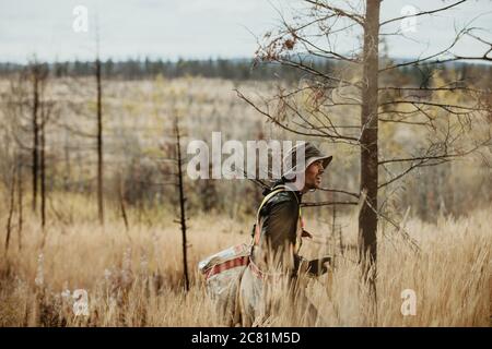 Homme marchant dans une zone de forêt déboisée transportant des sacs de nouveaux arbres. Ranger travaillant pour le reboisement dans la forêt. Banque D'Images