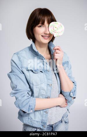 portrait de la jeune femme ou de la jeune fille qui couvre le visage avec une lipop sur fond gris Banque D'Images