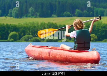 Joyeux garçon actif en vacances d'été. Adolescent ayant le plaisir de profiter de l'aventure expérience de kayak sur le lac lors d'une journée ensoleillée en été Banque D'Images