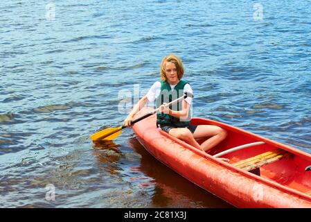 Joyeux garçon actif en vacances d'été. Adolescent ayant le plaisir de profiter de l'aventure expérience de kayak sur le lac lors d'une journée ensoleillée en été Banque D'Images