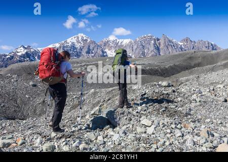 Couple et leur chien backpacking à travers la moraine du glacier Kennicott, montagnes Wrangell, Wrangell-St. Elias National Park, le centre-sud de l'Alaska Banque D'Images