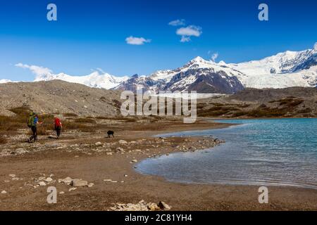 Couple et leur chien en marche arrière sur le soleil, jour d'été, après un des lacs glaciaires de Donoho, en direction du glacier de Kennicott et de la moraine, Wran... Banque D'Images