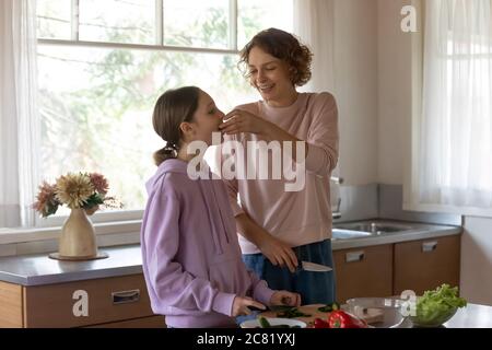 Une mère heureuse et une fille adolescente cuisent dans une cuisine moderne ensemble Banque D'Images