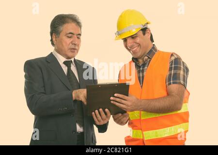 Happy senior man persan persan et les jeunes man construction worker smiling lors de la lecture sur le presse-papiers Banque D'Images