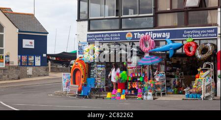 Une femme à l'extérieur de la boutique de plage de Slippway sur Cobb Road, Lyme Regis, Dorset. Banque D'Images